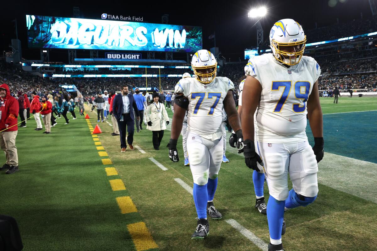 Chargers offensive tackle Trey Pipkins III and guard Zion Johnson (77) walk off the field. 