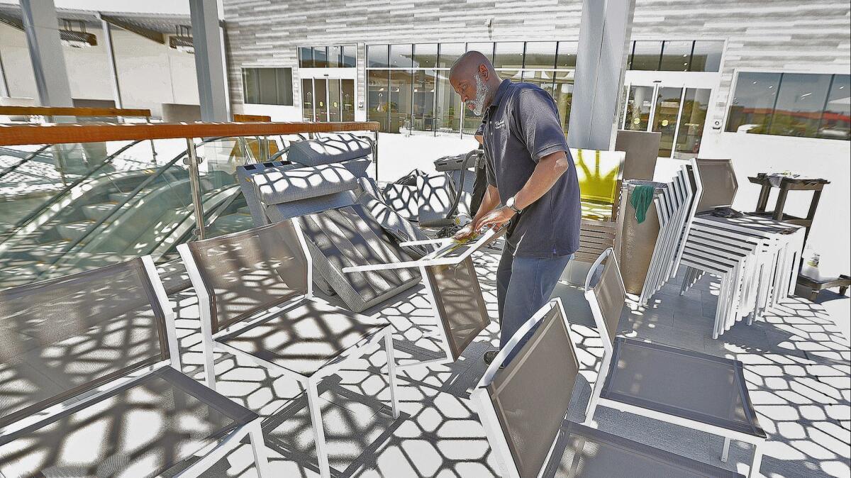 Burbank Town Center employee Jack Reddix, of Los Angeles, wipes down new chairs on the outdoor dining terrace at Burbank Town Center on Tuesday, June 12, 2018.
