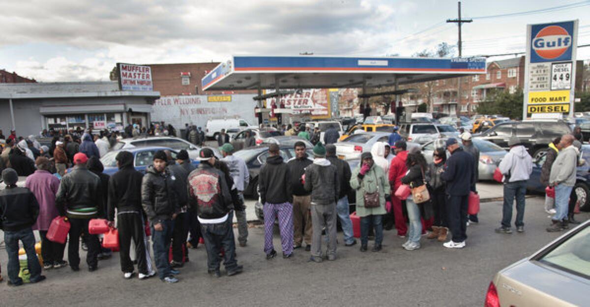 Customers with portable containers wait for gas pumps to open at a service station Saturday in Brooklyn.