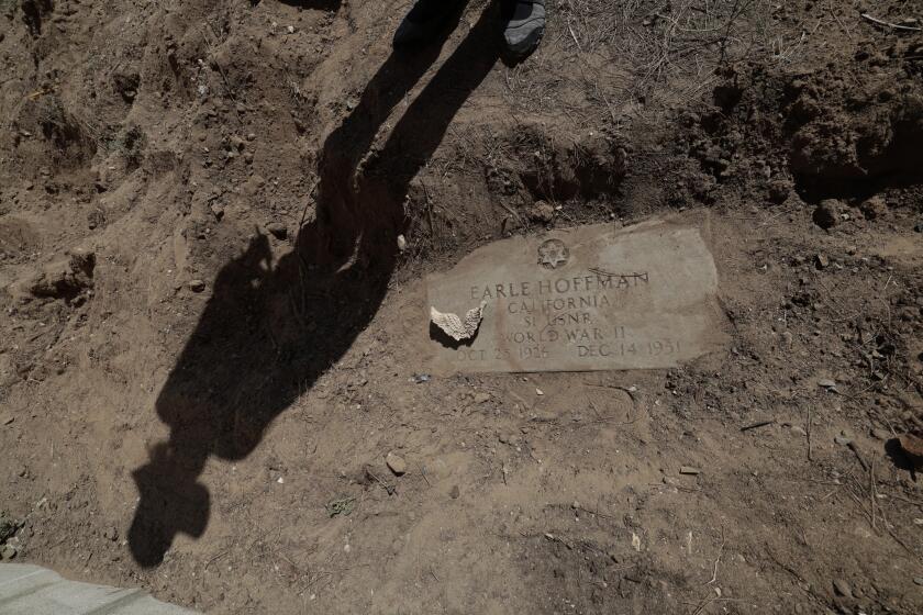 Lawndale, CA - September 28: An uncovered headstone of WWII veteran Earle Hoffman is viewed in the backyard of Josh Standifer's Lawndale home where Metro is considering building a new rail line Thursday, Sept. 28, 2023. Neighbors say that it has long been rumored that there are more than a dozen crypts in backyards. Standifer's property is adjacent to Metro-owned right of way. The track is currently used for freight, and is a proposed option for the Metro C Line extension to Torrance. (Allen J. Schaben / Los Angeles Times)