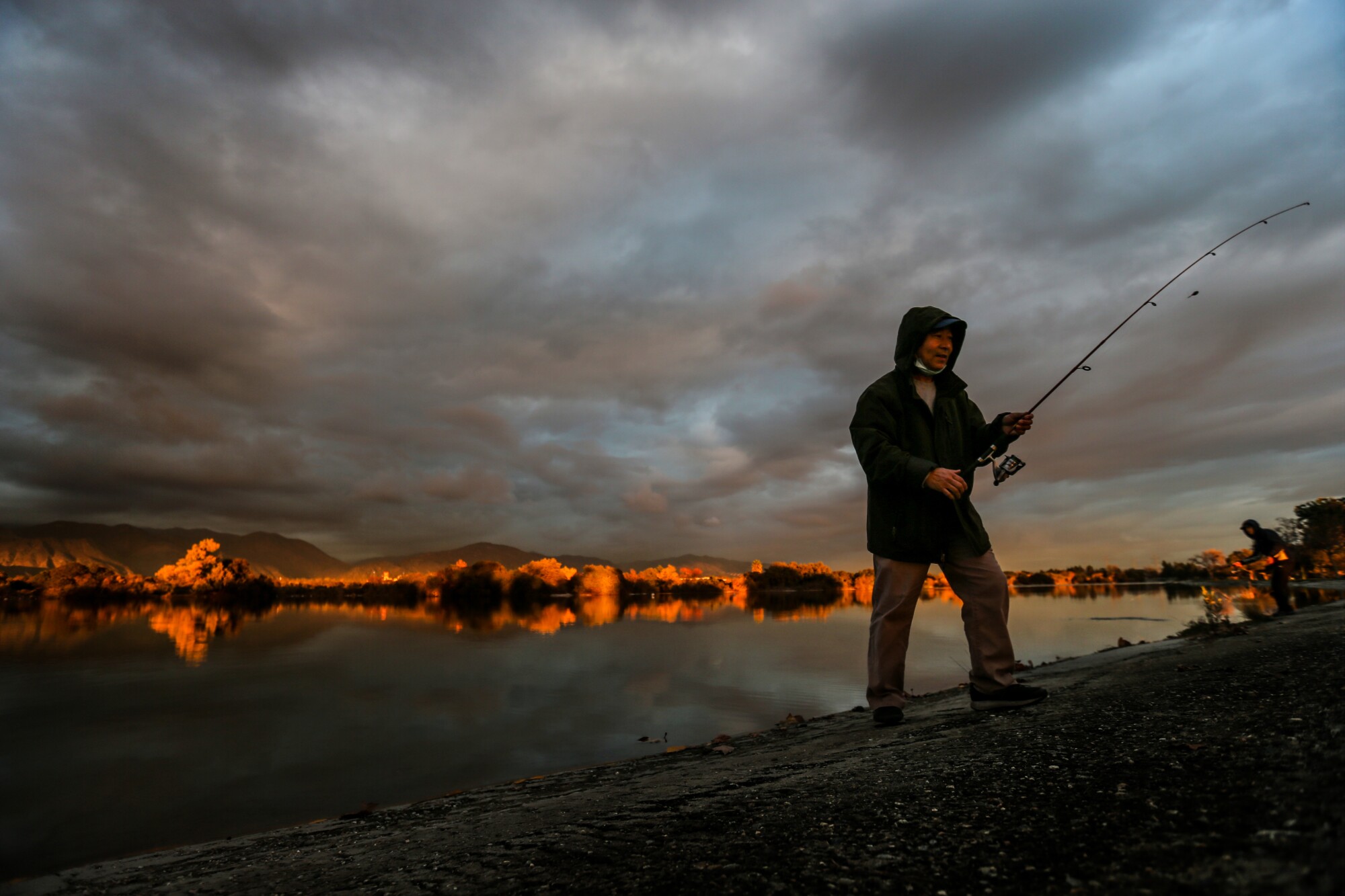 Ying Ten ends a fishing day on Tuesday as the sun sets with Santa Fe Dam glowing.