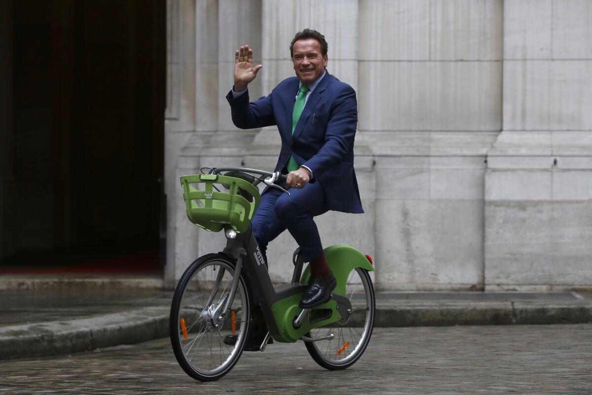 Arnold Schwarzenegger arrives by bicycle to meet Paris Mayor Anne Hidalgo on Monday.
