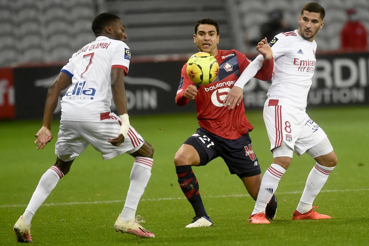 Lille's French midfielder Benjamin Andre, center, is challenged by Lyon's French midfielder Houssem Aouar, right, during the French League One soccer match between Lille and Olympique Lyonnais at the Pierre-Mauroy Stadium in Villeneuve d'Ascq, northern France, Sunday, Nov. 1, 2020. (Francois Lo Presti, Pool via AP)