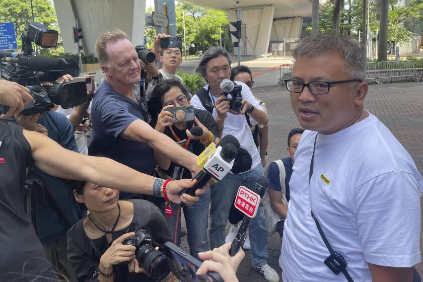 Hong Kong Journalists Association's Chairman Ronson Chan, right, speaks to reporters outside a court building in Hong Kong Monday, Sept. 25, 2023. The chairman of Hong Kong’s leading journalist group was found guilty of obstructing a police officer on Monday in a court case that sparked concerns about the city's declining press freedom. (AP Photo/Alice Fung)