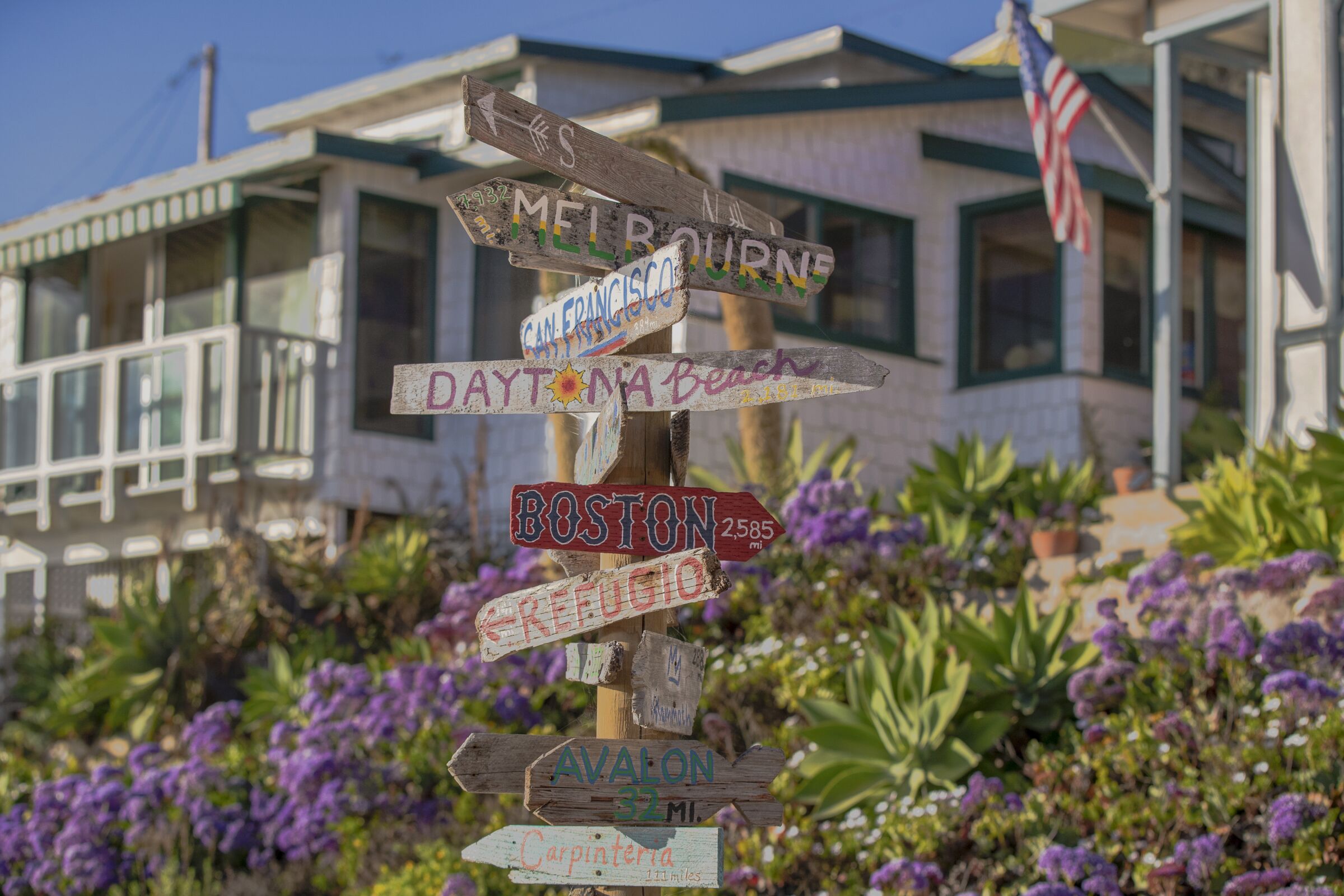A beachside cottage with a signpost pointing in several different directions.