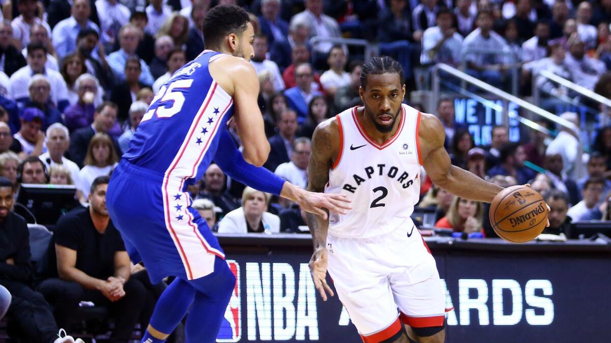 Toronto Raptors' Kawhi Leonard, right, dribbles the ball as Philadelphia 76ers' Ben Simmons defends in the second half during Game 5 of the second round of the NBA playoffs on Tuesday.