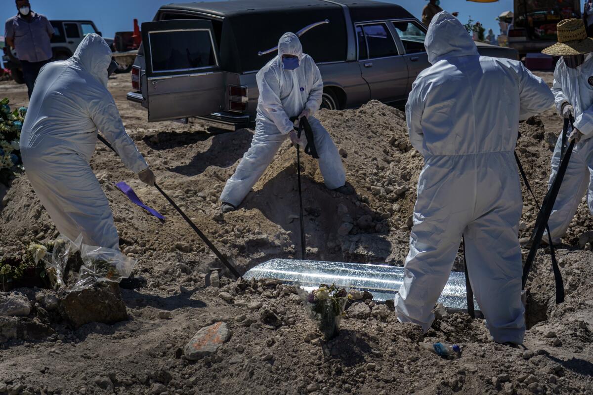 Workers in protective suits lower a coffin containing the remains of woman, who died of COVID-19, at a cemetery in Tijuana.