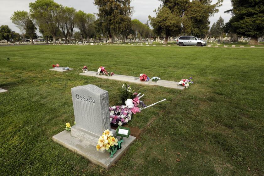 MADERA, CALIFORNIA-APRIL 8, 2020-Wanda Deselle, age 76, died of Covid 19 on April 3, 2020, in the town of Madera, California, where she worked in a medical office. Members of Jay Chapel Funeral Home bring the body to the gravesite. Immediate family had to remain in their cars as Deselle was buried on April 8, 2020. Employees of the funeral home and cemetery workers handled the burial and were the only ones allowed at the gravesite. (Carolyn Cole/Los Angeles Times)