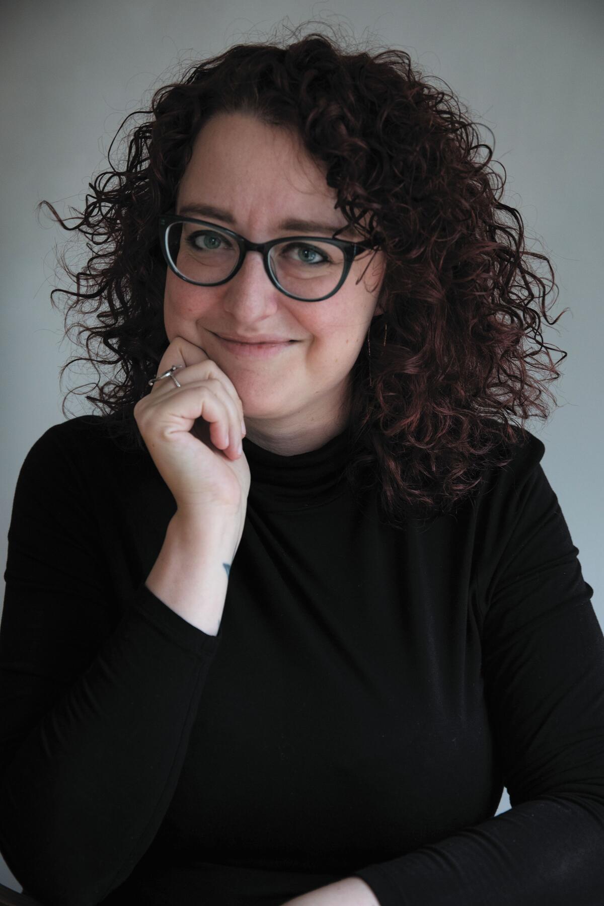 Headshot of a woman with glasses and curly hair 