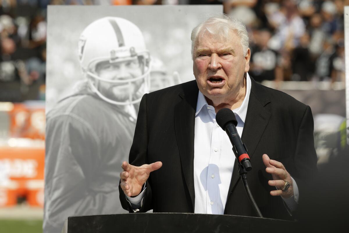 FILE - Former Oakland Raiders head coach John Madden speaks about former quarterback Ken Stabler, pictured at rear, during a ceremony honoring Stabler at halftime of an NFL football game between the Raiders and the Cincinnati Bengals in Oakland, Calif., on Sept. 13, 2015. The NFL is making that a lasting tribute by honoring the late broadcaster by launching “The Annual John Madden Thanksgiving Celebration” to begin on the first Thanksgiving following his death last December. The league plans for the Thanksgiving tribute to Madden to be an annual event starting Nov. 24 when there will be special segments on all three broadcasts by CBS, Fox and NBC dedicated to Madden. (AP Photo/Ben Margot, File)