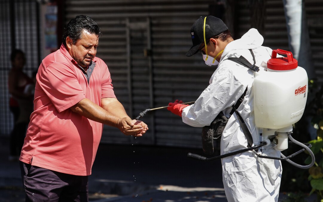 MEXICO: A worker sprays disinfectant on a man's hands in Guadalajara.