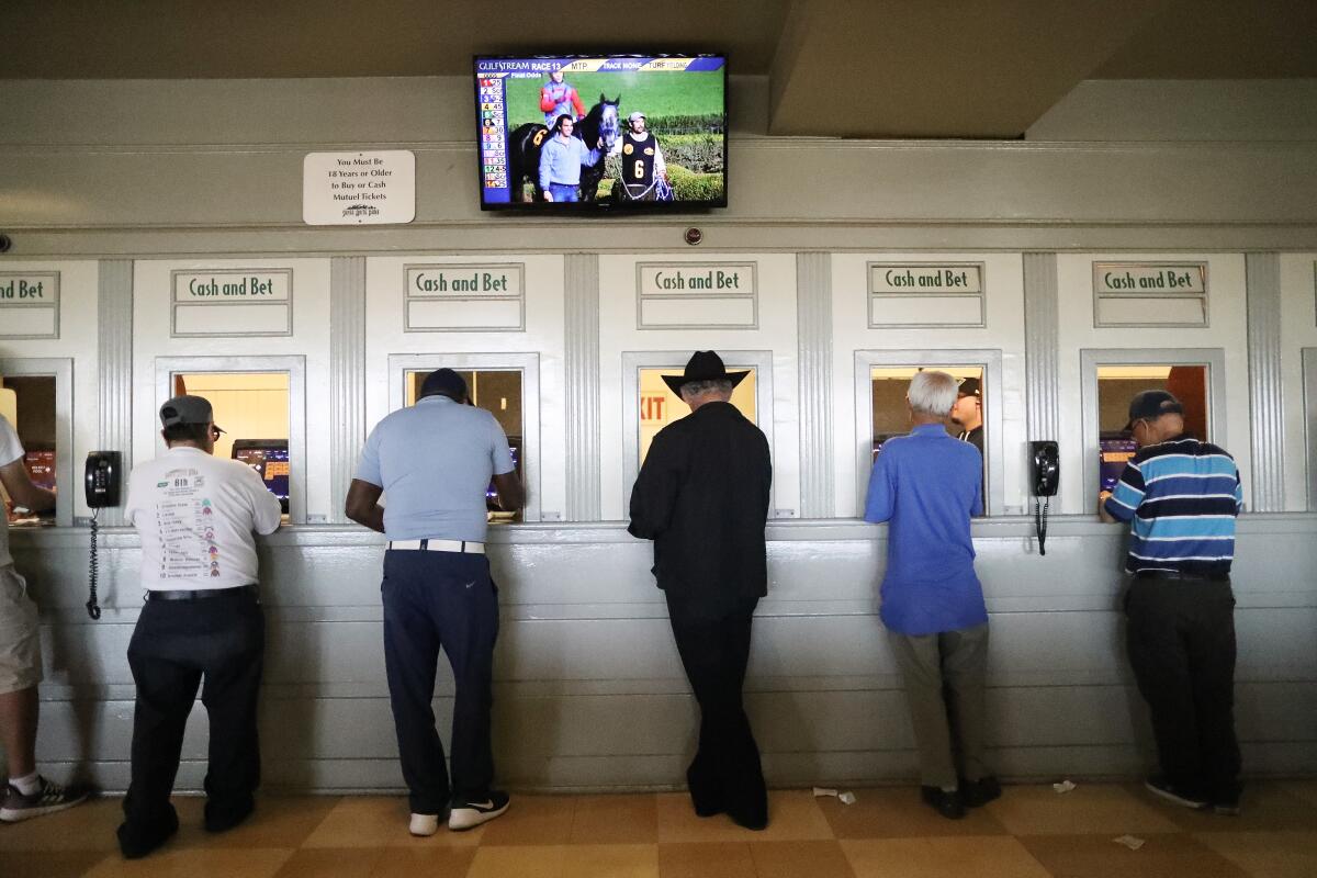People stand at betting windows.