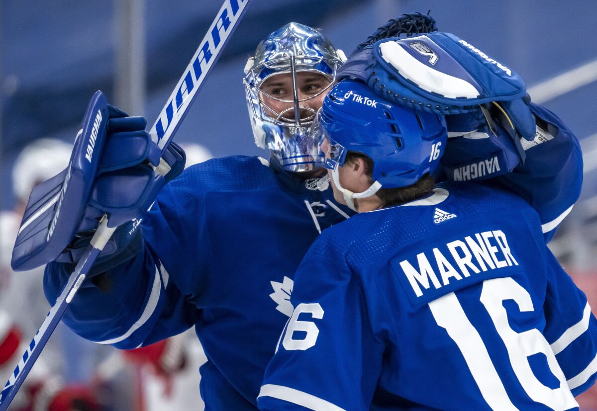 Toronto Maple Leafs goaltender Petr Mrazek (35) and right wing Mitchell Marner (16) celebrate after defeating the Carolina Hurricanes in overtime of an NHL hockey game in Toronto, Monday, Feb. 7, 2022. (Frank Gunn/The Canadian Press via AP)