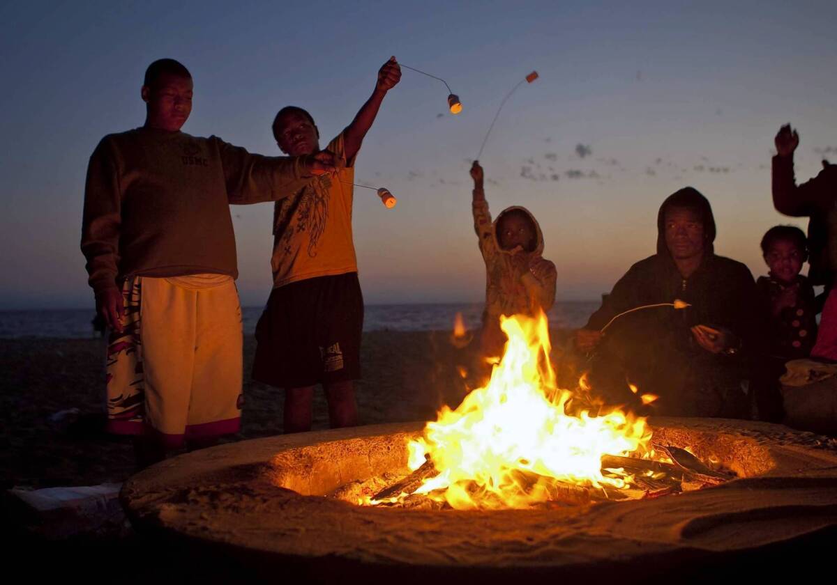Members of the Sasser-Williams family roast marshmallows as they gather around a bonfire at Dockweiler Beach in Playa del Rey