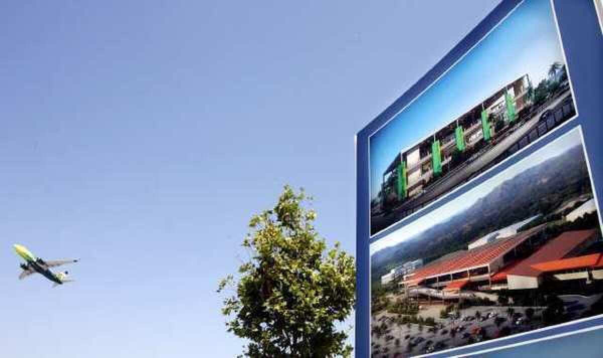 A plane takes off in the background as renderings of the new transit center are displayed at the Bob Hope Airport.