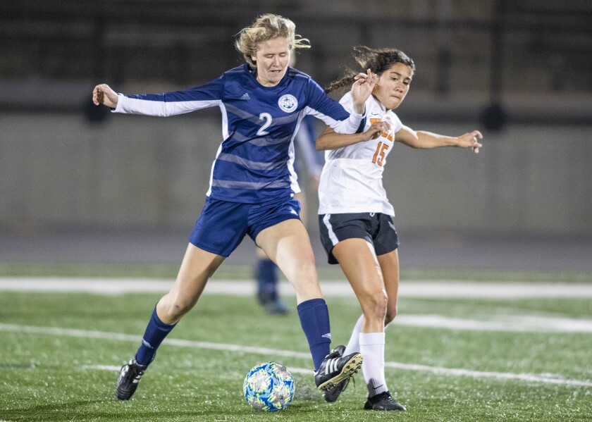 Newport Harbor's Emmie Degen, left, battles for a ball against Huntington Beach's Ashley Adams in a Sunset Conference crossover match on Thursday in Newport Beach.