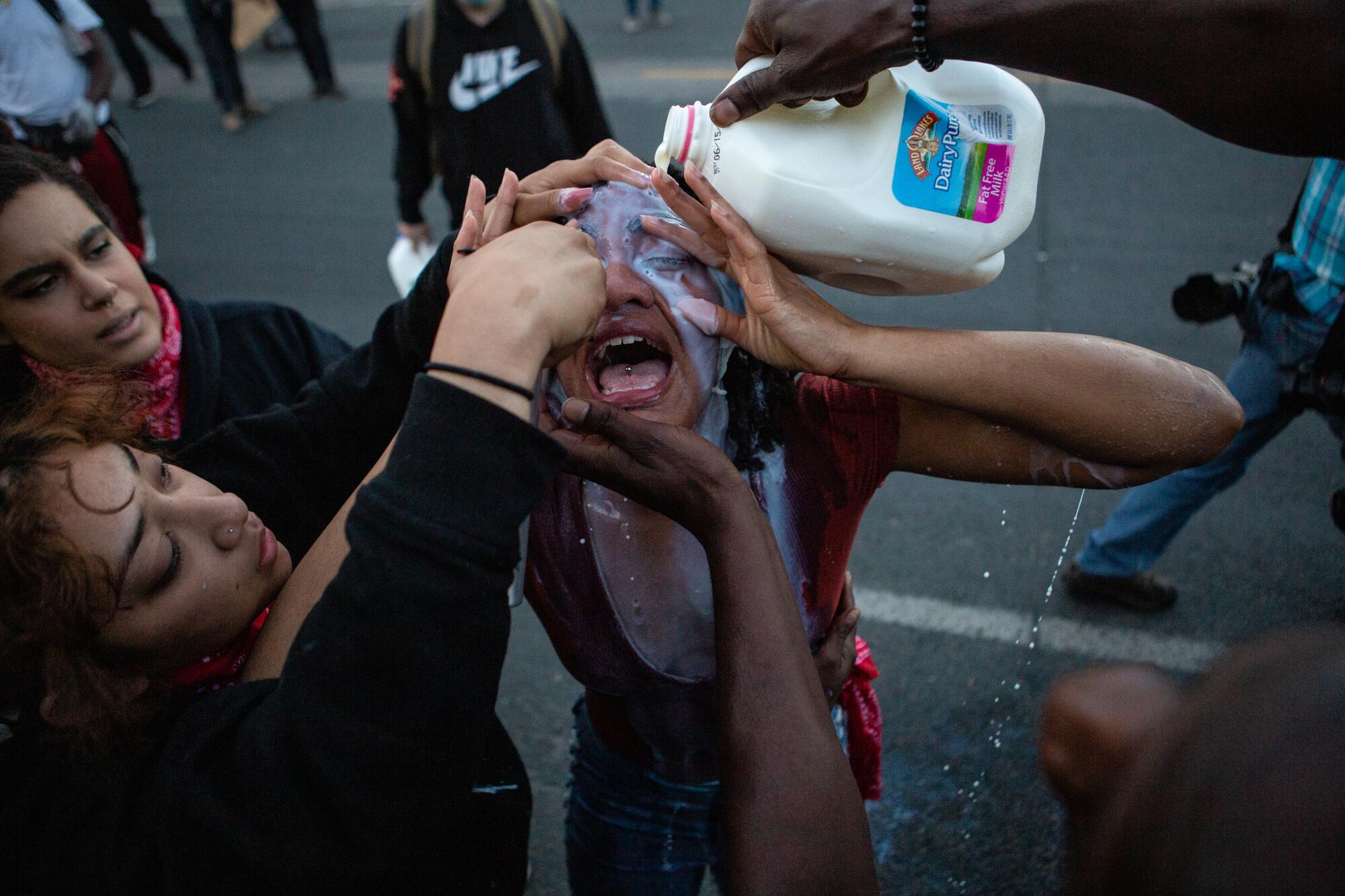 Los manifestantes usan leche para ayudar a una mujer afectada por gases lacrimógenos disparados por la policía cerca de la 5ta estación del distrito electoral en Minneapolis.
