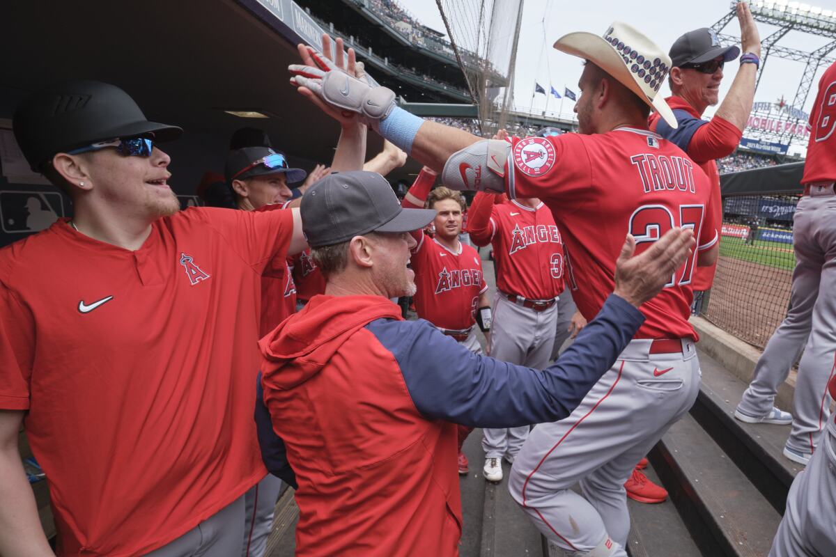 Los Angeles Angels' Mike Trout, right, is greeted in the dugout after hitting a two-run home run on a pitch from Seattle Mariners starting pitcher Logan Gilbert during the fourth inning of a baseball game, Sunday, June 19, 2022, in Seattle. (AP Photo/John Froschauer)