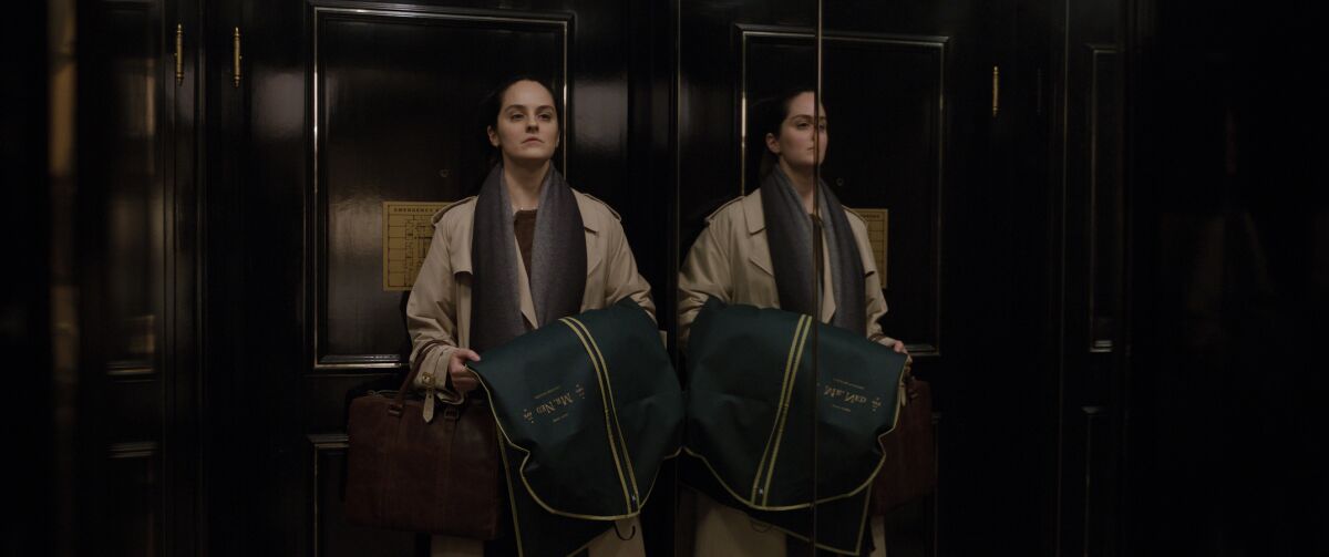 A woman holds a garment bag while in an elevator in the movie "Tár."