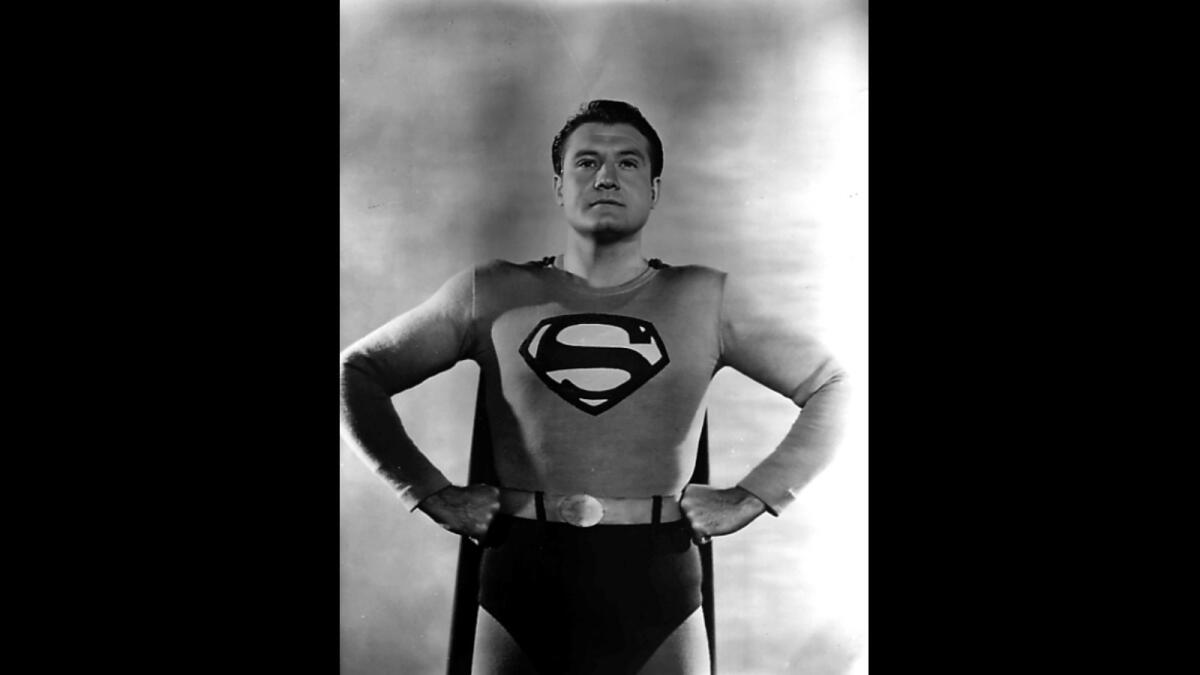 George Reeves in Superman costume with hands on hips