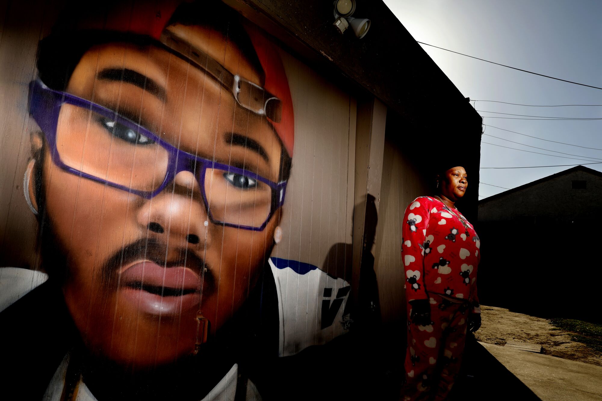 Latasha Bracks stands next to a mural of her son Tashon Logan