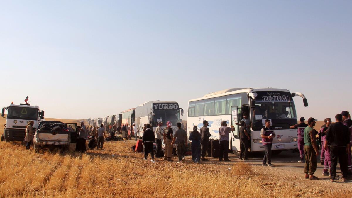 Syrian civilians and fighters who were evacuated from northeastern Lebanon gather near buses after crossing into the rebel-held area of Al-Saan in Syria on Aug. 3.