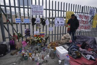 Un altar con velas y fotos cubre la cerca afuera del centro de detención de migrantes que fue el sitio de un incendio mortal, mientras los migrantes se despiertan después de pasar la noche en la acera en Ciudad Juárez, México, el jueves 30 de marzo de 2023. (AP Foto/Fernando Llano)