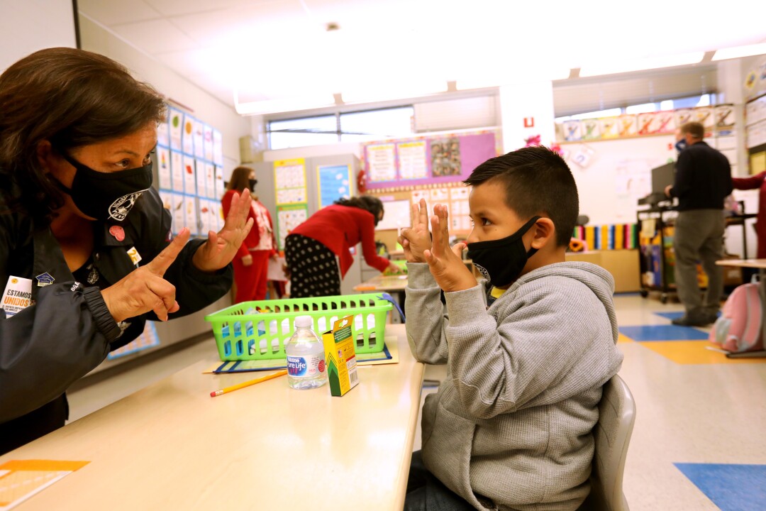 Photos: Tears and cheers after more than a year as LAUSD
resumes in-class instruction 5 A woman and boy hold up their fingers.