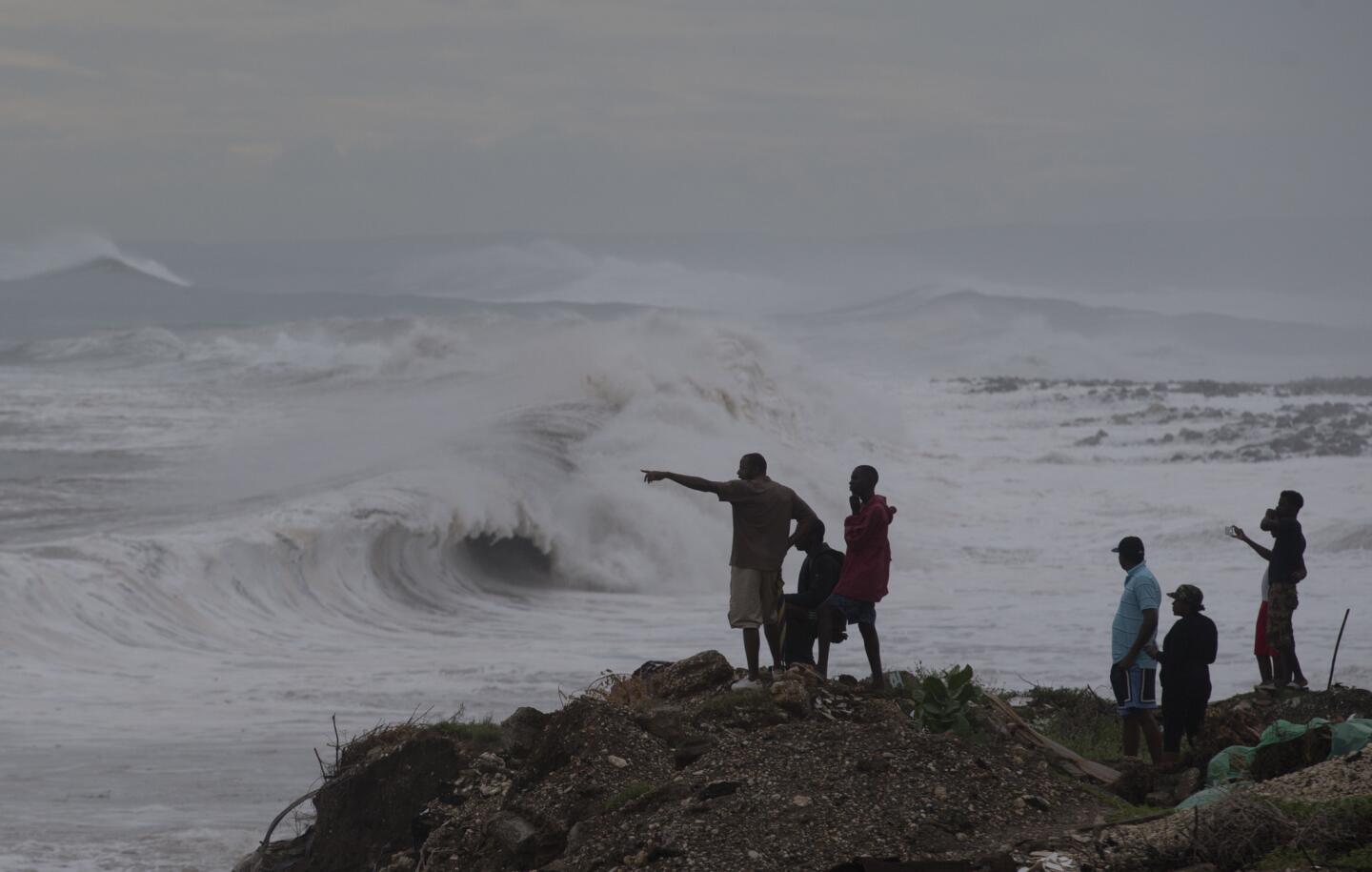 People stand on the coast watching the surf produced by Hurricane Matthew on the outskirts of Kingston, Jamaica, on Oct. 3, 2016.