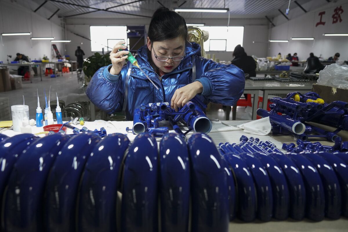 FILE - In this photo released by Xinhua News Agency, a worker assembles western musical instruments at a manufacturer factory in in Wuqiang County, north China's Hebei province on Feb. 23, 2023. A government survey shows China’s factory activity grew at a slower pace in March but was stronger than expected following the end of anti-virus restrictions. (Mu Yu/Xinhua via AP, File)