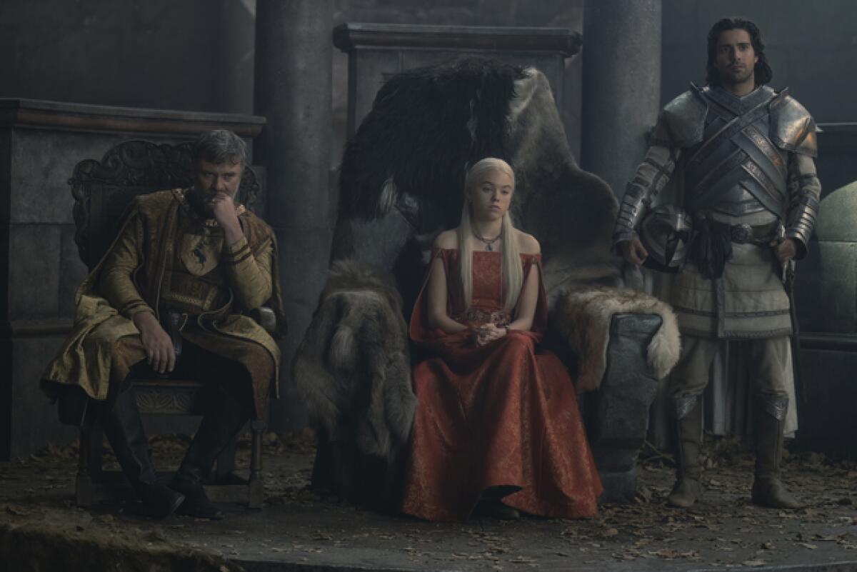 A princess sits between an advisor and a knight as she takes visits from suitors.