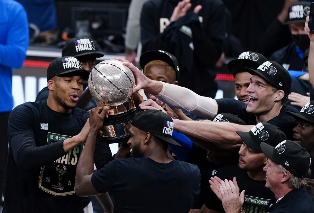 Bucks players hoist the Eastern Conference title trophy after defeating the Hawks in Game 6 on July 3, 2021, in Atlanta.