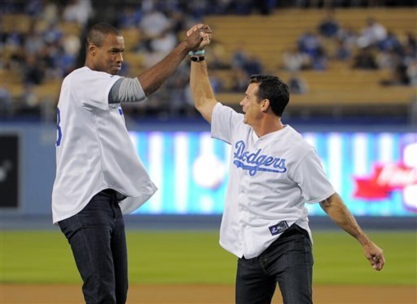 Basketball player Jason Collins, left, and former baseball player Billy Bean congratulate each other after throwing out the ceremonial first pitches at the first annual LGBT Night Out at Dodger Stadium, prior to the Los Angeles Dodgers' baseball game against the Colorado Rockies, Friday, Sept. 27, 2013, in Los Angeles. (AP Photo/Mark J. Terrill)