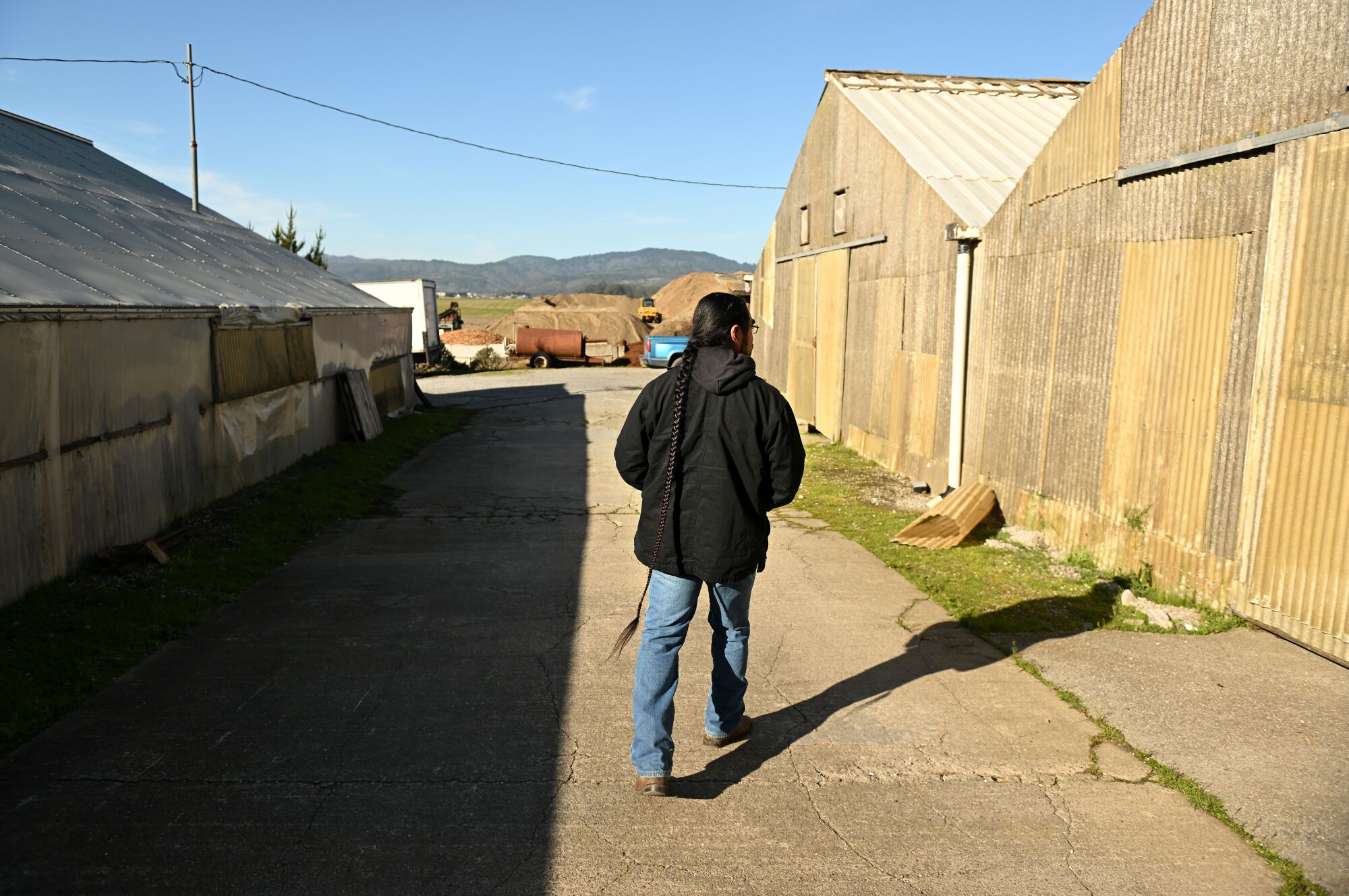 A man walks away from the camera between rows of metal roofed buildings