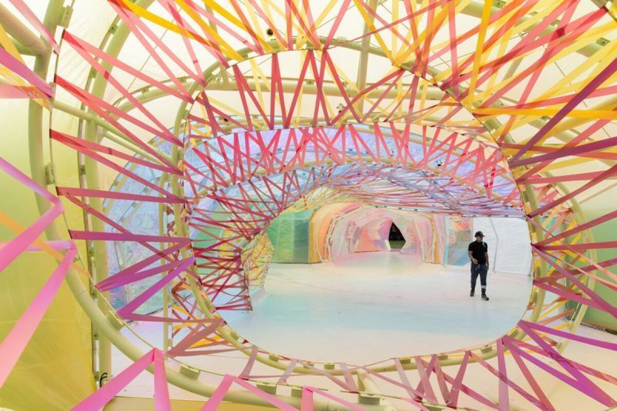 A view through pink ribbons to a structure sheathed in translucent polymer.