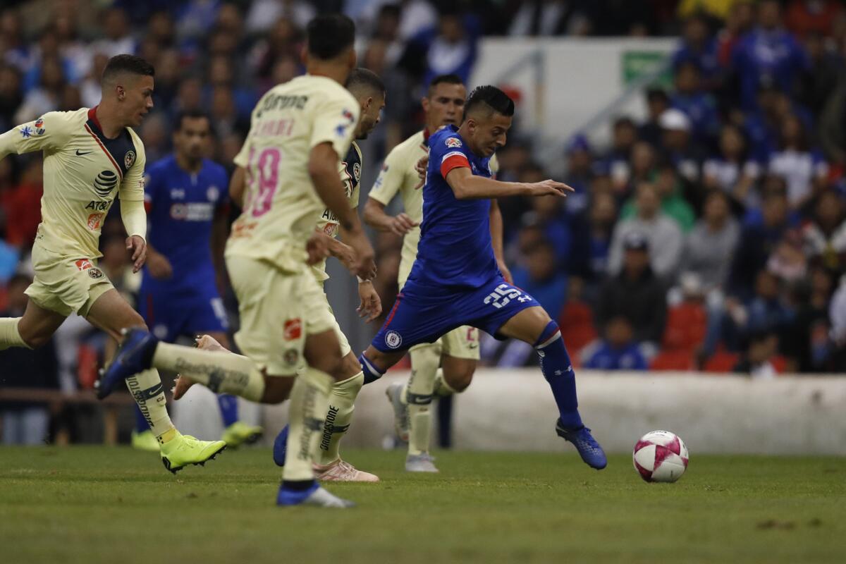 Roberto Alvarado (derecha) de Cruz Azul se desmarca con el balón frente a jugadores del América en un partido del torneo Apertura de México, el sábado 27 de octubre de 2018.