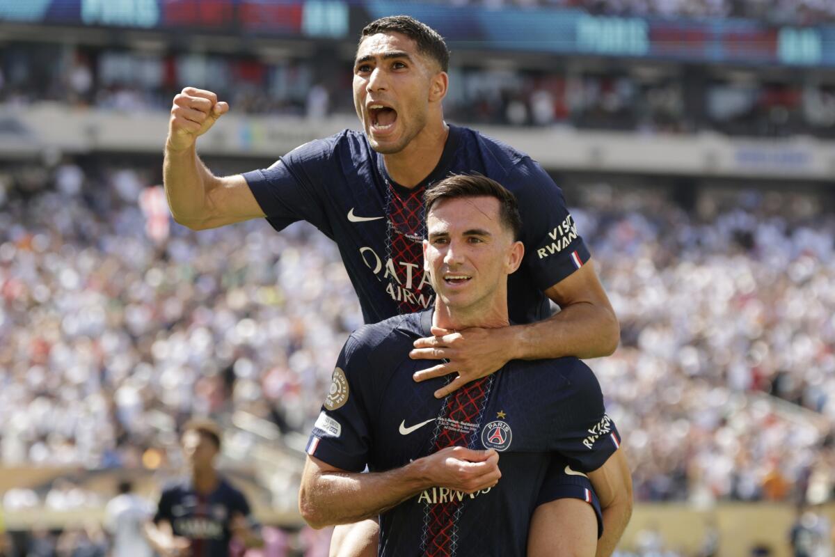 Paris Saint-Germain's Fabian Ruiz, bottom, celebrates with teammate Achraf Hakimi after scoring his team's third goal.