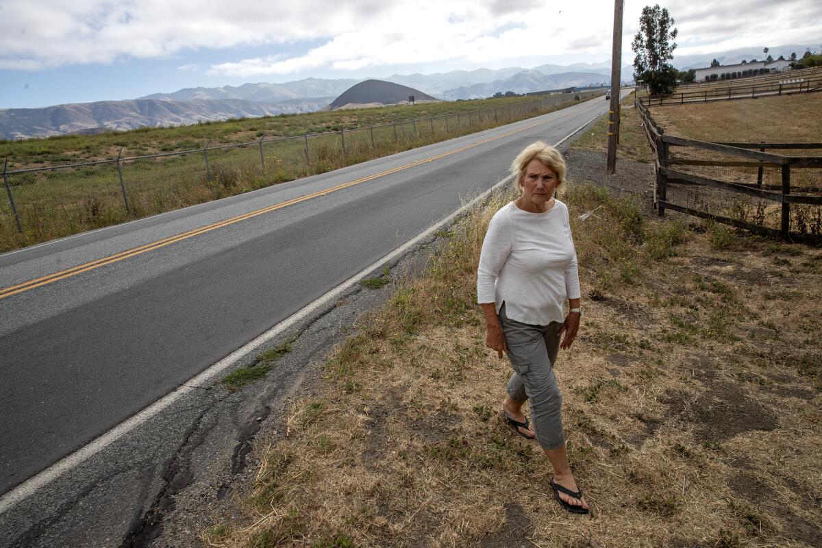 A woman walks beside a rural highway