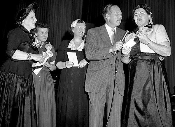 Emcee Art Linkletter interviews Mrs. Bernard A. Koteen, 37, of Washington, D.C., right, during the awards ceremony in New York after she won the $25,000 grand prize in Pillsbury Mills bake-off with her Open Sesame Pie recipe. Mrs. Richard Enloe, third from right, of Atlanta, won the second prize of $7,500, and Mrs. Kenneth B. Kennedy, second from left, of Mahtomedi, Minn., won the third prize of $2,500. At left is Nina Warren, wife of Chief Justice Earl Warren, who took part in ceremonies. See full story