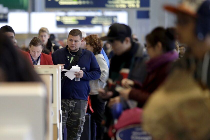 Travelers check their tickets and walk to their gates at O'Hare International Airport on Sunday, Nov. 29, 2015, in Chicago. Tens of millions of Americans returning home after the long Thanksgiving holiday weekend Sunday have cooperative weather and mostly efficient airport operations to thank for smooth traveling conditions. (AP Photo/Nam Y. Huh)