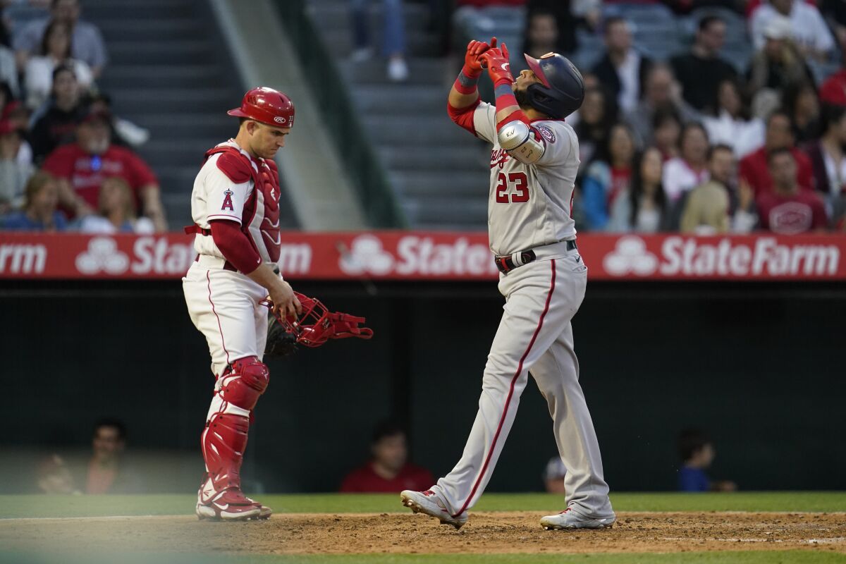 Washington Nationals designated hitter Nelson Cruz (23) points to the sky as he crosses home plate after hitting a home run during the fifth inning of a baseball game against the Los Angeles Angels in Anaheim, Calif., Saturday, May 7, 2022. Josh Bell also scored. (AP Photo/Ashley Landis)