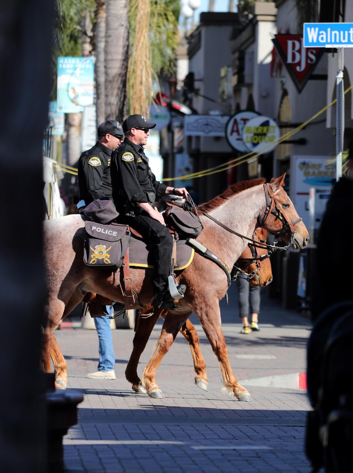 Two mounted police officers carry out a training exercise on Main Street in Huntington Beach on Wednesday.