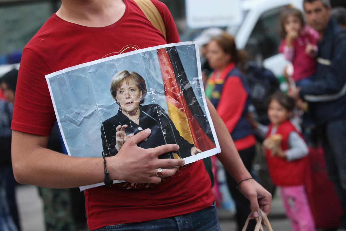 A migrant from Syria holds a picture of German Chancellor Angela Merkel as he and hundreds of others arrive at Munich's main railway station on Sept. 5.