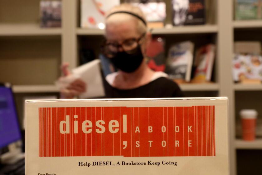 BRENTWOOD, CA - SEPTEMBER 10, 2020 - - Bookseller Lynn Aime makes a sale next to a sign that asks customers to help with their GoFundMe account inside the book store in Brentwood on September 10, 2020. Diesel, A Bookstore is trying to raise $400,000 to help it survive the economic downturn caused by the coronavirus pandemic. Since mid-March, sales drops have fluctuated 55% to 80%, yet its debt continues to mount. To date the GoFundMe account has raised over $75,000. (Genaro Molina / Los Angeles Times)