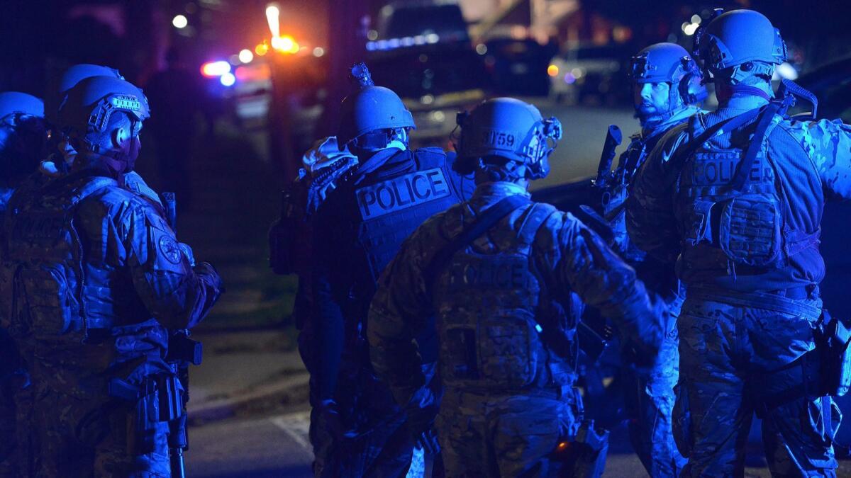 A SWAT team prepares to search the neighborhood where a police officer was fatally shot Friday in New Kensington, Pa.