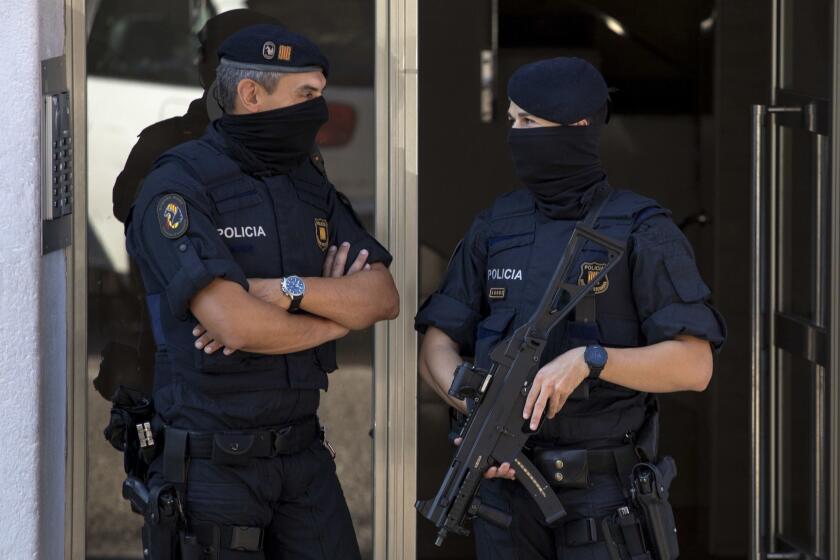 Catalan police officers stand guard at the entrance of a building during a raid, following an attack in Cornella de Llobregat near Barcelona, Spain, Monday, August 20, 2018. Police in Barcelona say they have shot a man who attacked officers with a knife at a police station in the Spanish city, saying in a tweet Monday the attack occurred just before 6 a.m. in the Cornella district of the city. (AP Photo/Emilio Morenatti)