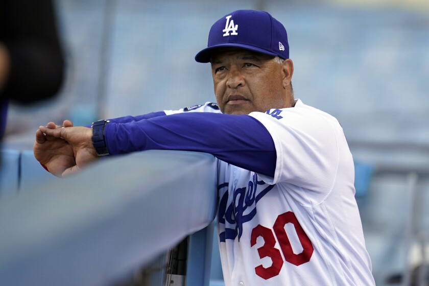Dodgers manager Dave Roberts looks on in the dugout during a baseball game.