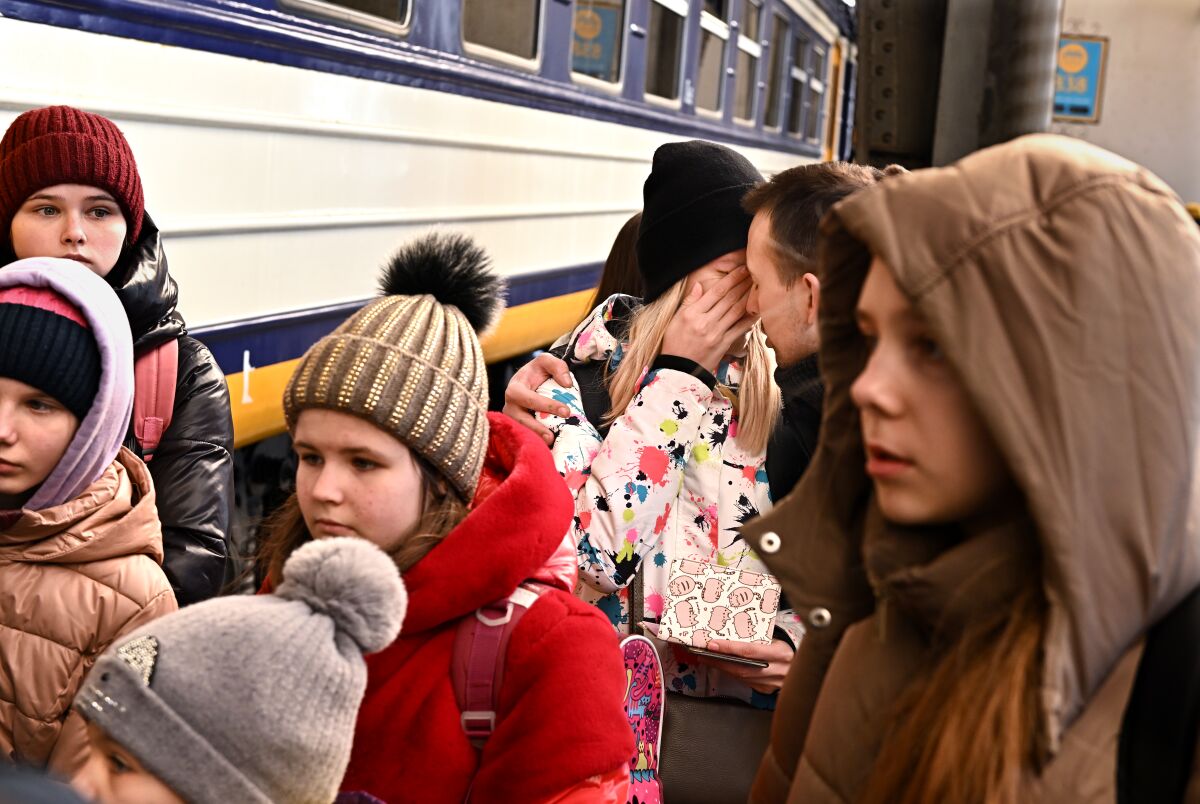 A man comforts his wife before she boards a train