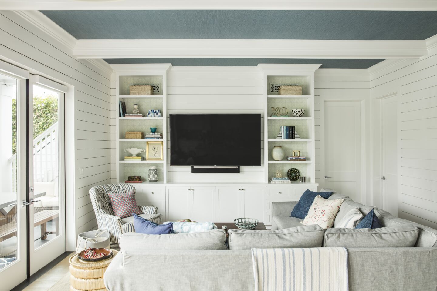 ... and after. Interior designer Christine Markatos Lowe toned down the white shiplap with blue grasscloth on the ceiling and a new built-in entertainment center.