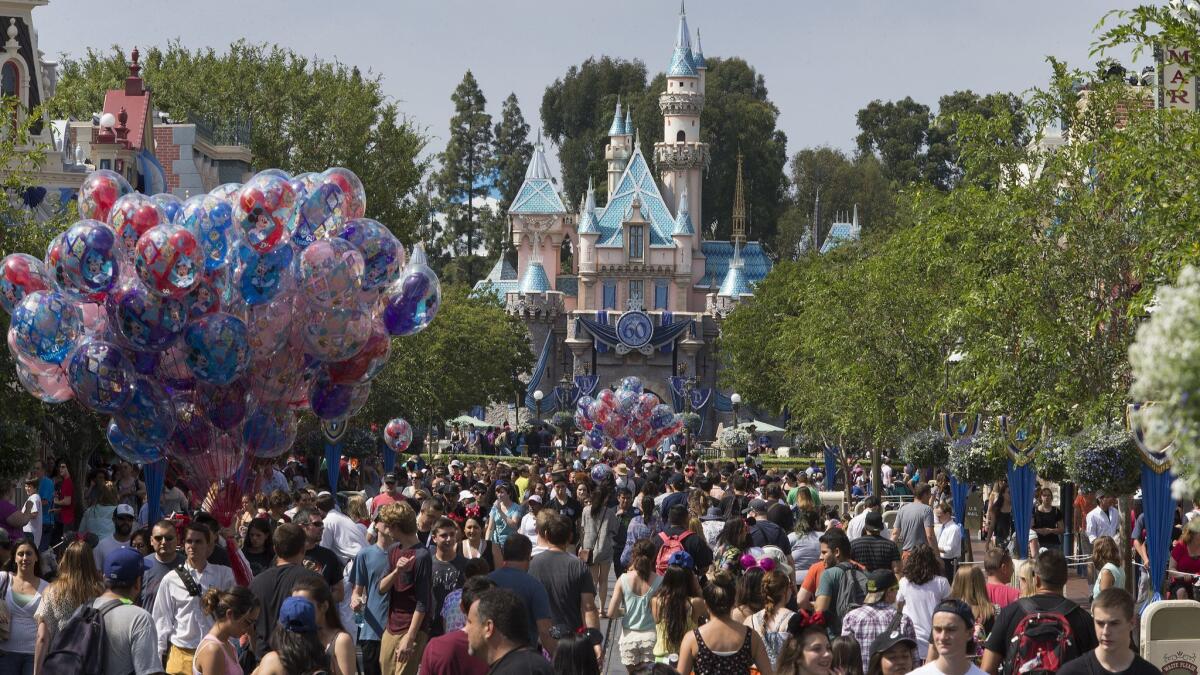 A large crowd strolls down Main Street during Disneyland's diamond jubilee celebration in June 2015. A petition to require major employers who receive city subsidies to pay a "living wage" has qualified for the Anaheim ballot.